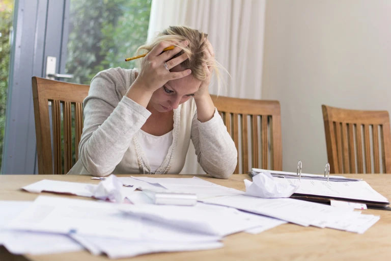 stressed woman with debt sitting at a table