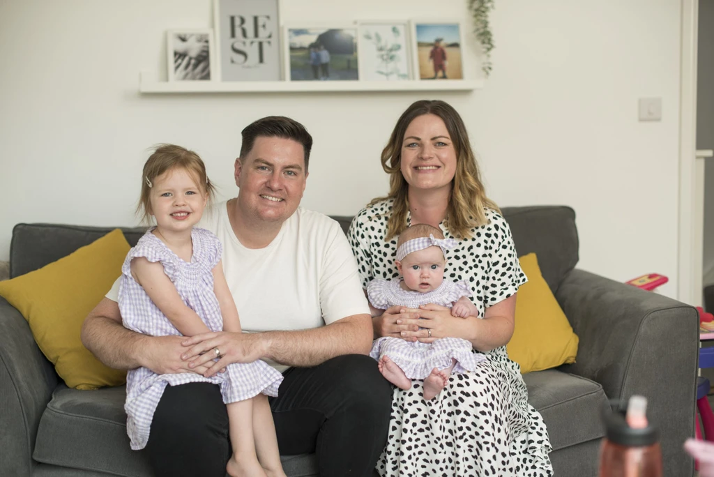 Tony and Sarah and their young daughters sitting on the sofa in their home in Whitehouse, Milton Keynes