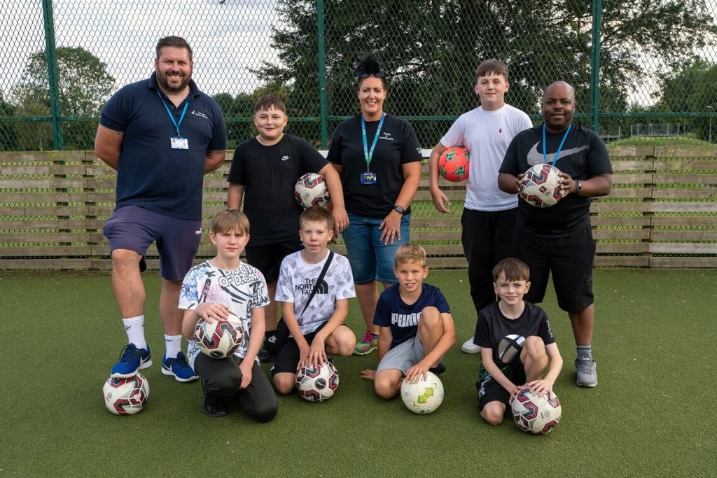 Nicola King and other mentors with a group of young people holding footballs