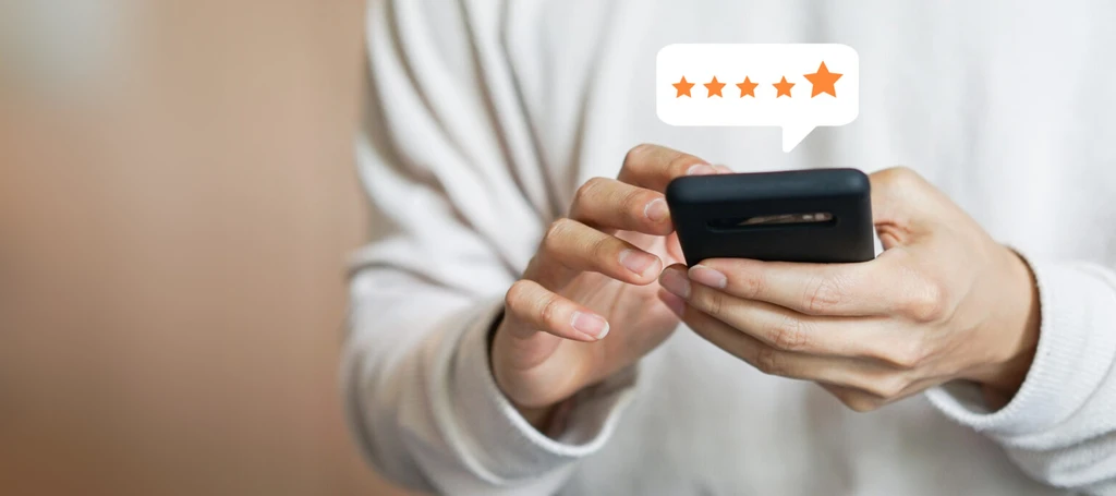 Close up of a man using a mobile phone to click on a 5 star rating