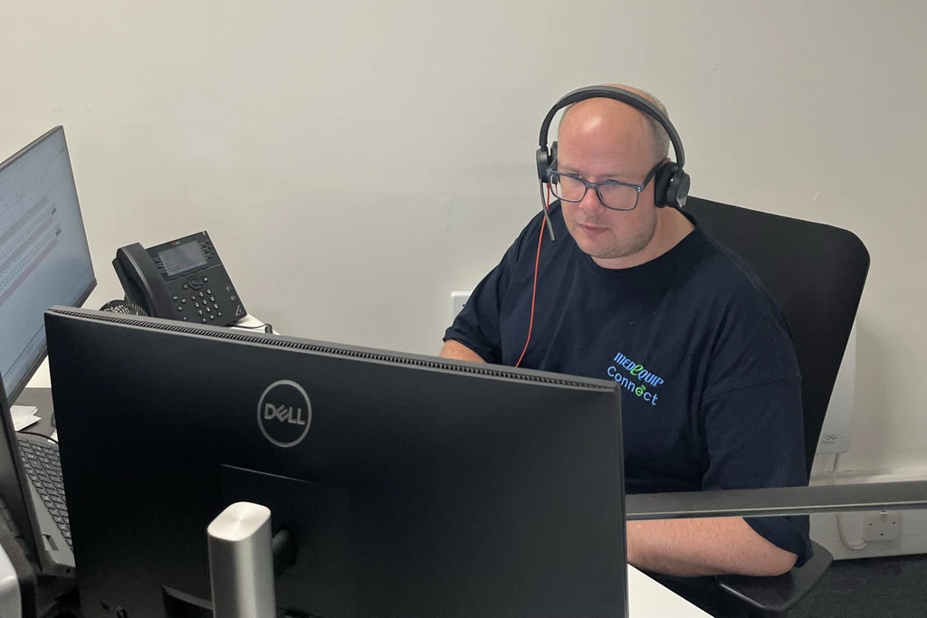 Medequip Connect employee looking at their computer and wearing a headset