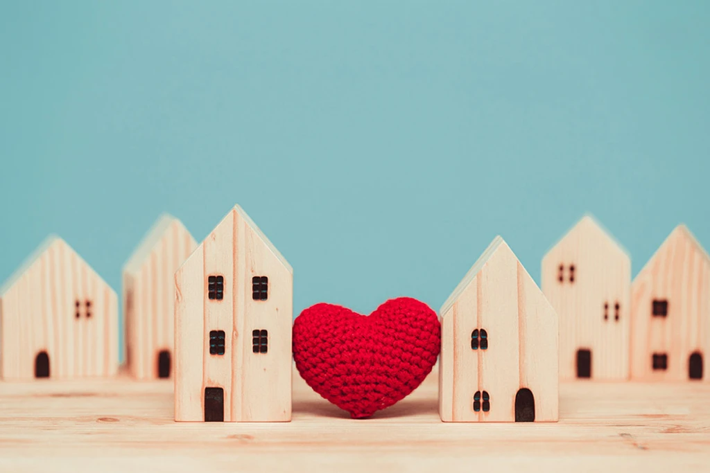 Love heart between two wooden house models.