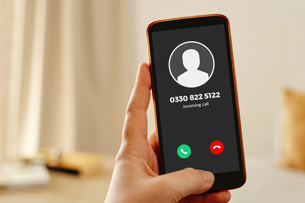 A hand holding a mobile phone displaying an incoming call from 0330 822 5122